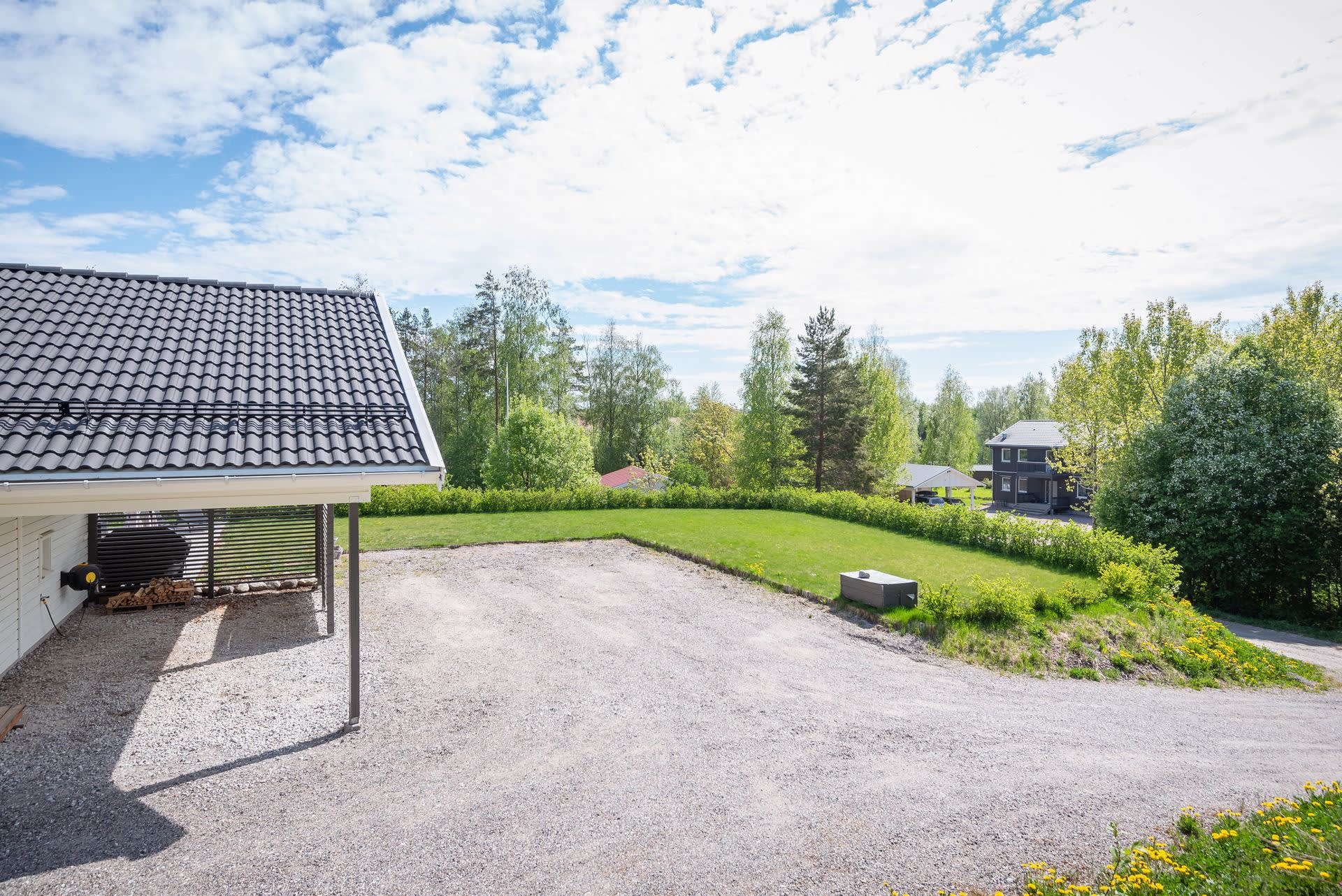 Carport och plats för flera bilar på grusplan.